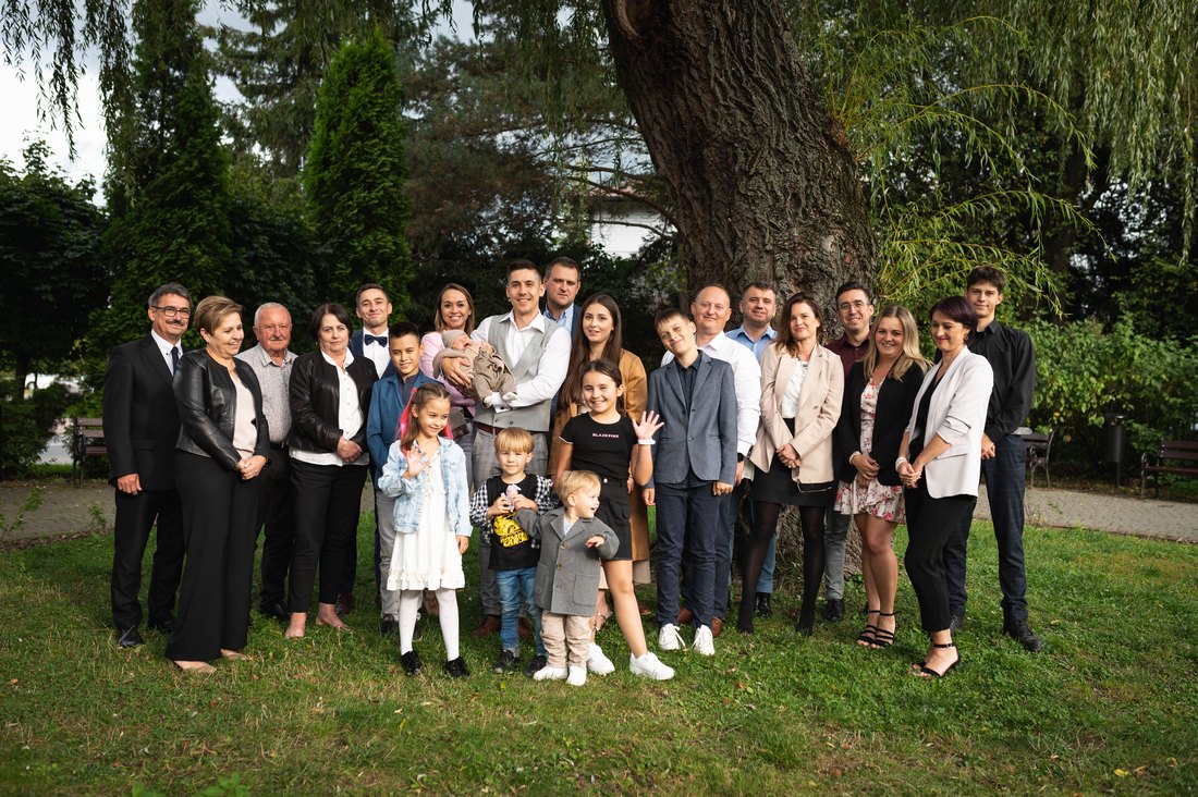 Wielopokoleniowe zdjęcie rodzinne pod drzewem — dziadkowie, rodzice i dzieci